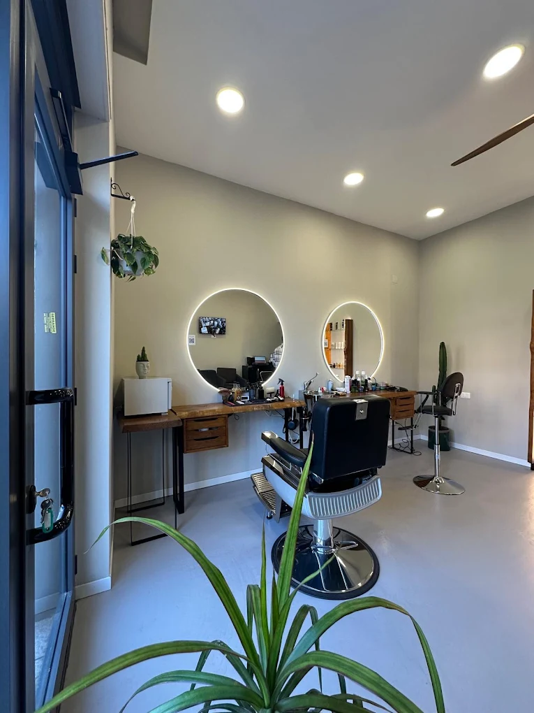 Arredamento interno di Feivèr Barber a Treviglio con specchi circolari a LED e poltrone da barbiere.